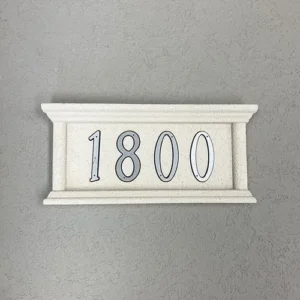 A rectangular Address Plaque mounted on a textured wall showcases the number 1800 in large, bold black numerals with subtle white outlines and features a decorative border with a classic, elegant style.